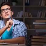 a boy in blue shirt thinking about writing the first line of the essay