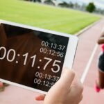 a girl runing on track while coach recording time on a device