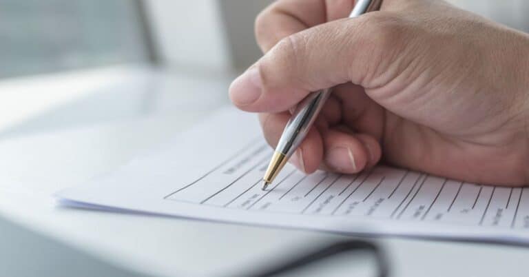 a boy writting on a application for with pen