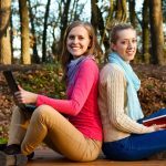 Students sitting back to back in a forest