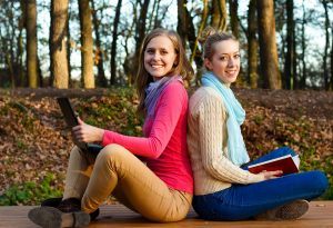 Students sitting back to back in a forest