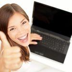 student smiling holding laptop