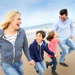 a man and women with children runing at a beach