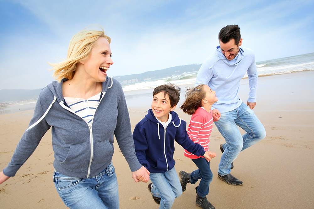 a man and women with children runing at a beach