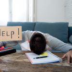 Young tired and stressed student working on his homework, masters feeling desperate and frustrated asking for help. In over Education, learning difficulties, finals exams and emotional stress concept.