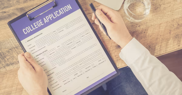 A person holds a clipboard displaying a college application form, the crisp white paper contrasting with the dark, navy-blue border. Their hands, one gripping a pen, rest on a rustic wooden table. A clear glass of water glimmers nearby, evoking a calm, studious atmosphere.