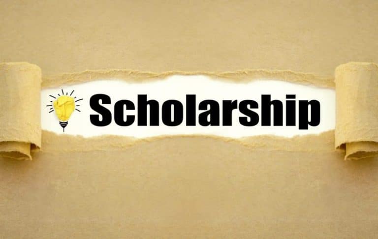 A torn paper reveals the word Scholarship in bold black letters, with a yellow lightbulb drawing on the left, symbolizing ideas or opportunities. The background is a textured light brown paper.