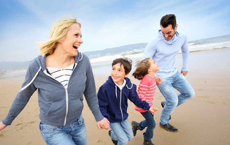 a man and women with children runing at a beach