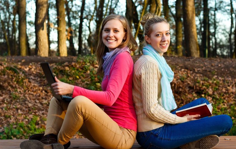 Students sitting back to back in a forest