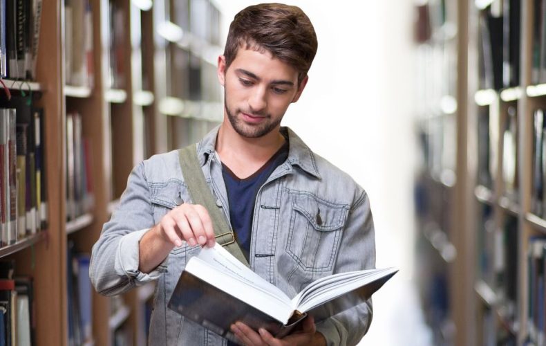 a boy reading book in the library