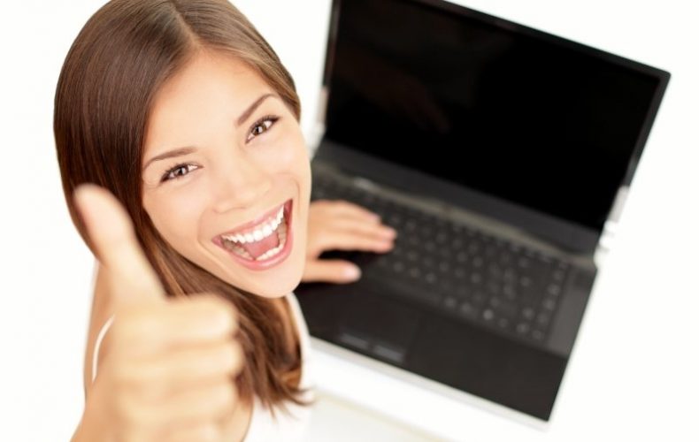 student smiling holding laptop